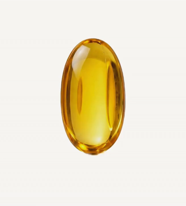 Golden oregano oil softgel capsule standing upright against a cream background